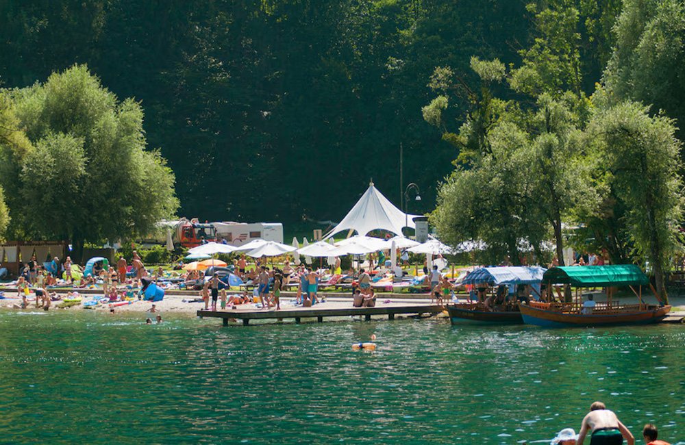 Strand aan het meer met bootjes bij camping bled in het triglav nationaal park van Slovenië