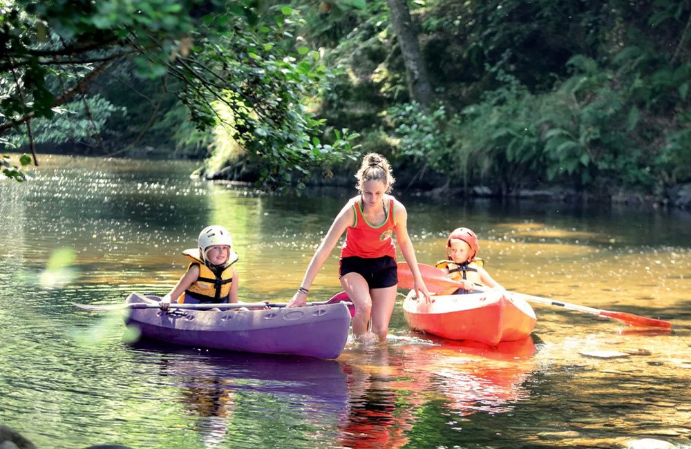 Kinderen in kano's op rivier de Dunière bij Camping de Vaubarlet in de Auvergne van Frankrijk